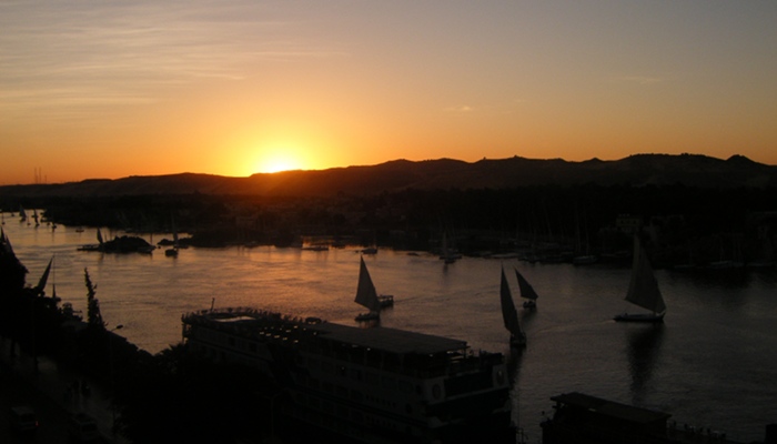 Feluccas and cruise ships on the Nile in Aswan at sunset.
