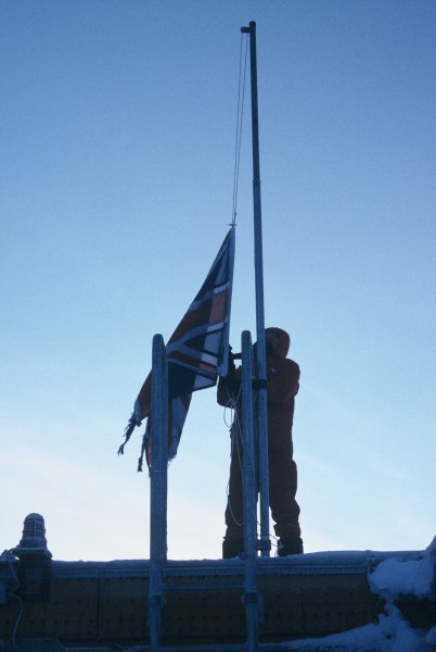 The oldest winterer lowering the British flag on the last day the sun was above the horizon during the winter.